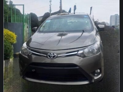 Image 6 (Rear Direct View): Direct rear view of 2015 Toyota Yaris sedan featuring code 2 plate placement and Toyota Yaris badges.
