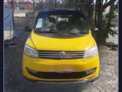 Front fascia view of the yellow 2018 Dongfeng Fengguang 330 compact passenger van showing headlights and grille